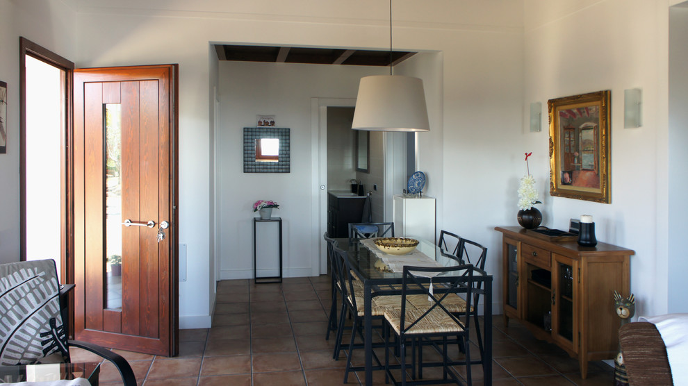 Foto di una piccola sala da pranzo aperta verso il soggiorno country con pareti bianche e pavimento con piastrelle in ceramica