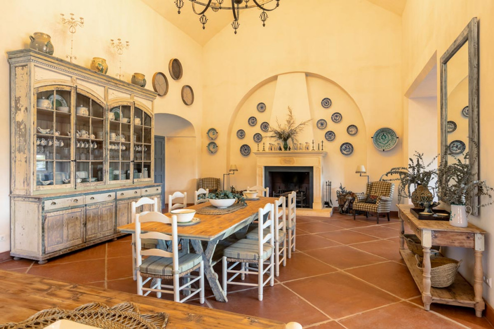 Idee per una sala da pranzo mediterranea con pareti gialle, camino classico e pavimento marrone