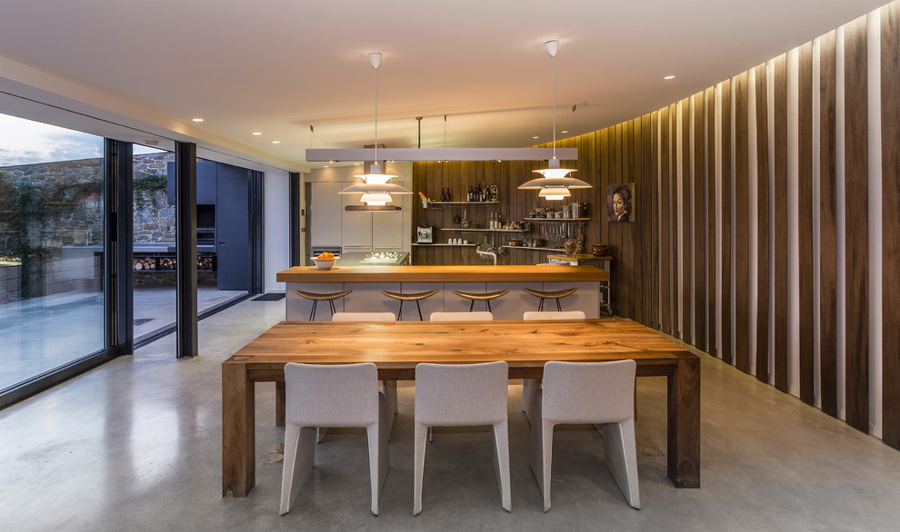 Immagine di una grande sala da pranzo aperta verso la cucina design con pavimento in cemento