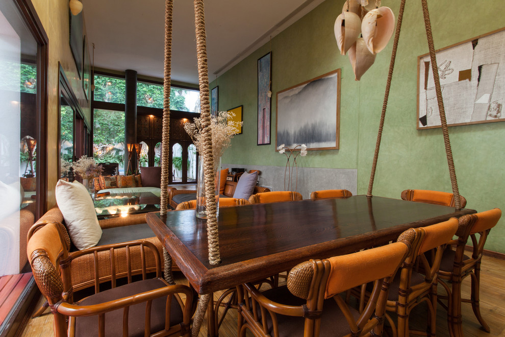 Ejemplo de comedor tropical grande abierto sin chimenea con paredes verdes y suelo de madera en tonos medios