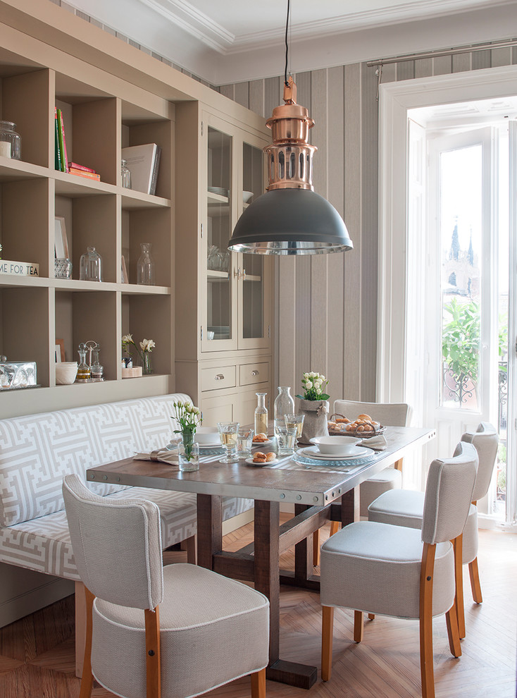 Idée de décoration pour une salle à manger ouverte sur la cuisine tradition avec parquet clair, un sol marron et un mur gris.