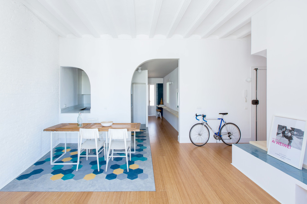Imagen de comedor costero con paredes blancas y suelo de madera en tonos medios