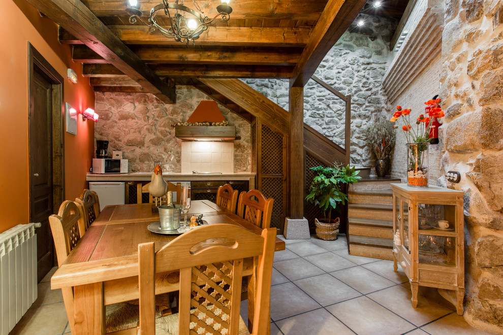 Inspiration pour une salle à manger ouverte sur la cuisine chalet de taille moyenne avec un mur orange, tomettes au sol, aucune cheminée et éclairage.