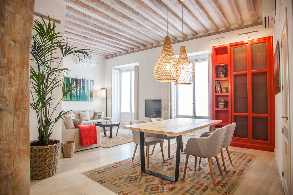 Medium sized mediterranean open plan dining room in Madrid with light hardwood flooring, white walls, beige floors and feature lighting.