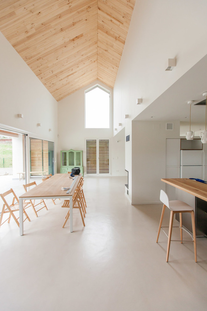 Modelo de comedor de cocina escandinavo extra grande sin chimenea con paredes blancas, suelo de cemento y suelo beige