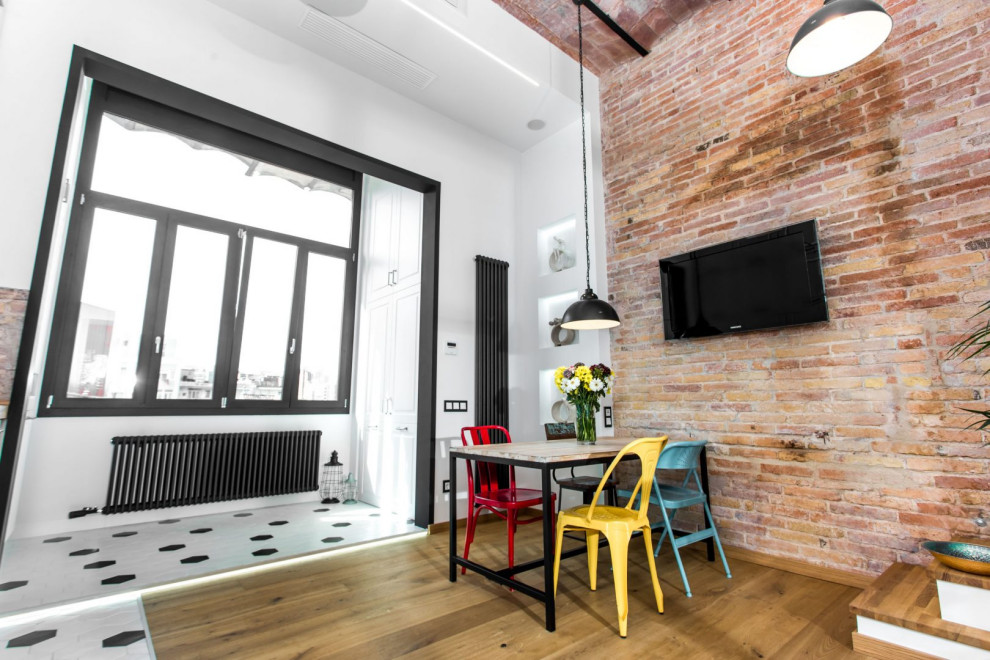 Foto di una grande sala da pranzo aperta verso la cucina industriale con pareti marroni, pavimento in legno massello medio, pavimento bianco, soffitto a volta e pareti in mattoni