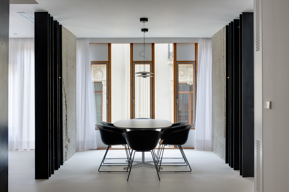 Imagen de comedor minimalista abierto con paredes blancas, suelo de cemento y suelo blanco