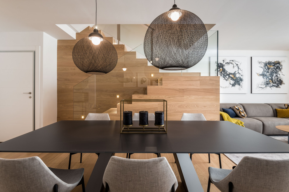 Ejemplo de comedor minimalista de tamaño medio abierto con paredes blancas, suelo de madera clara, suelo marrón y madera