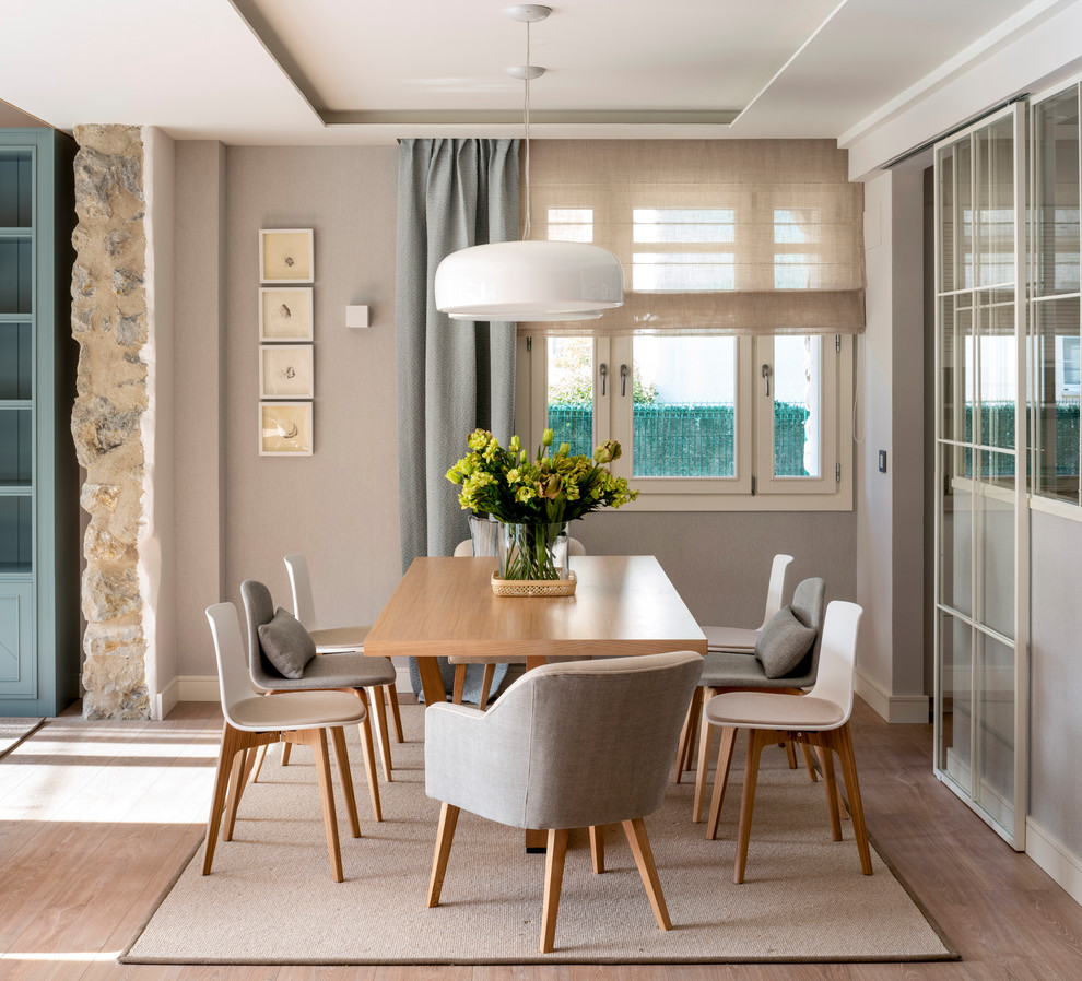 Inspiration for a large scandi dining room in Bilbao with laminate floors, no fireplace, brown floors and beige walls.