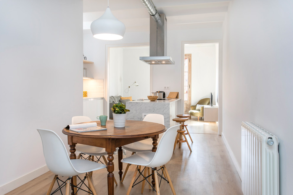 Immagine di una sala da pranzo aperta verso la cucina design di medie dimensioni con pareti bianche, nessun camino, pavimento marrone e parquet chiaro