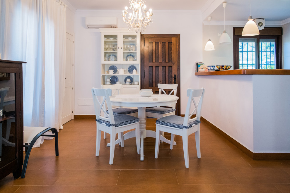 Foto di una piccola sala da pranzo aperta verso il soggiorno mediterranea con pareti bianche, pavimento con piastrelle in ceramica e nessun camino