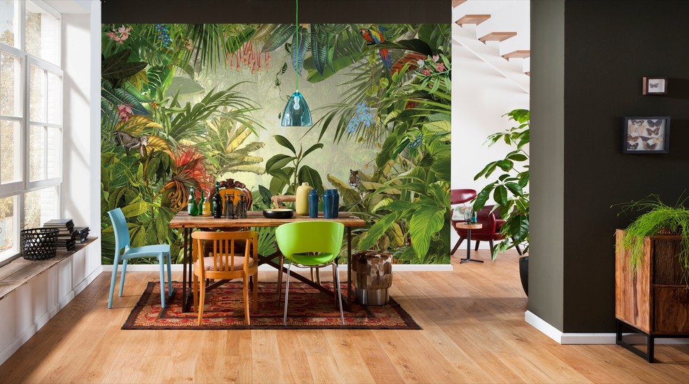Immagine di una sala da pranzo aperta verso il soggiorno tropicale di medie dimensioni con pareti verdi, parquet chiaro e nessun camino