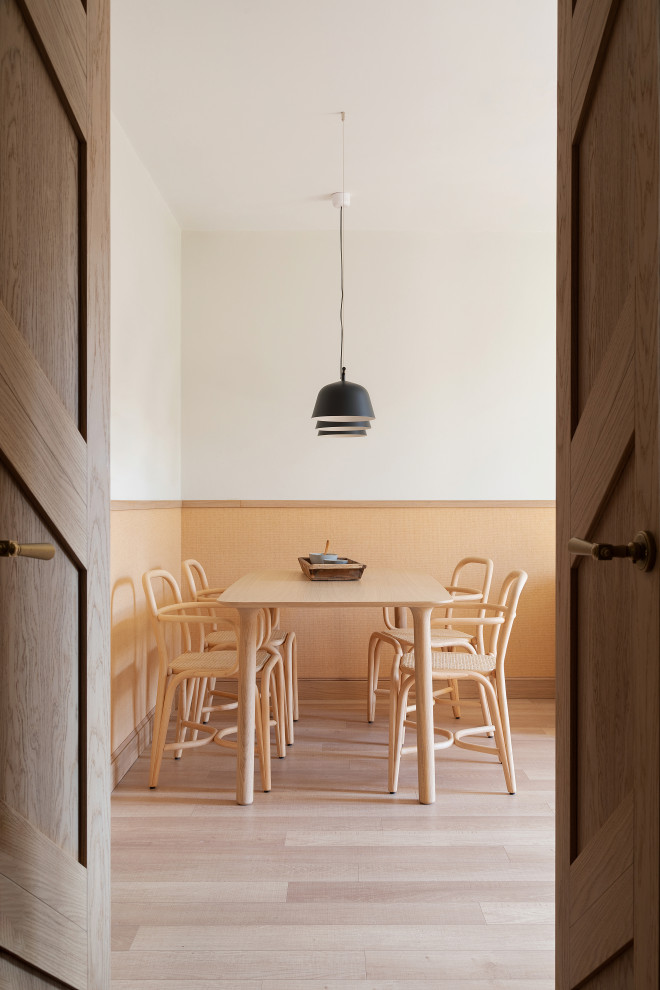 Ispirazione per una sala da pranzo design con pareti bianche, parquet chiaro, pavimento beige e boiserie