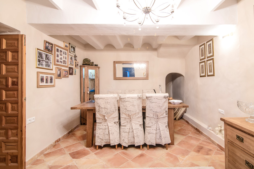 Foto di una sala da pranzo mediterranea chiusa con pareti bianche, pavimento in terracotta e pavimento marrone