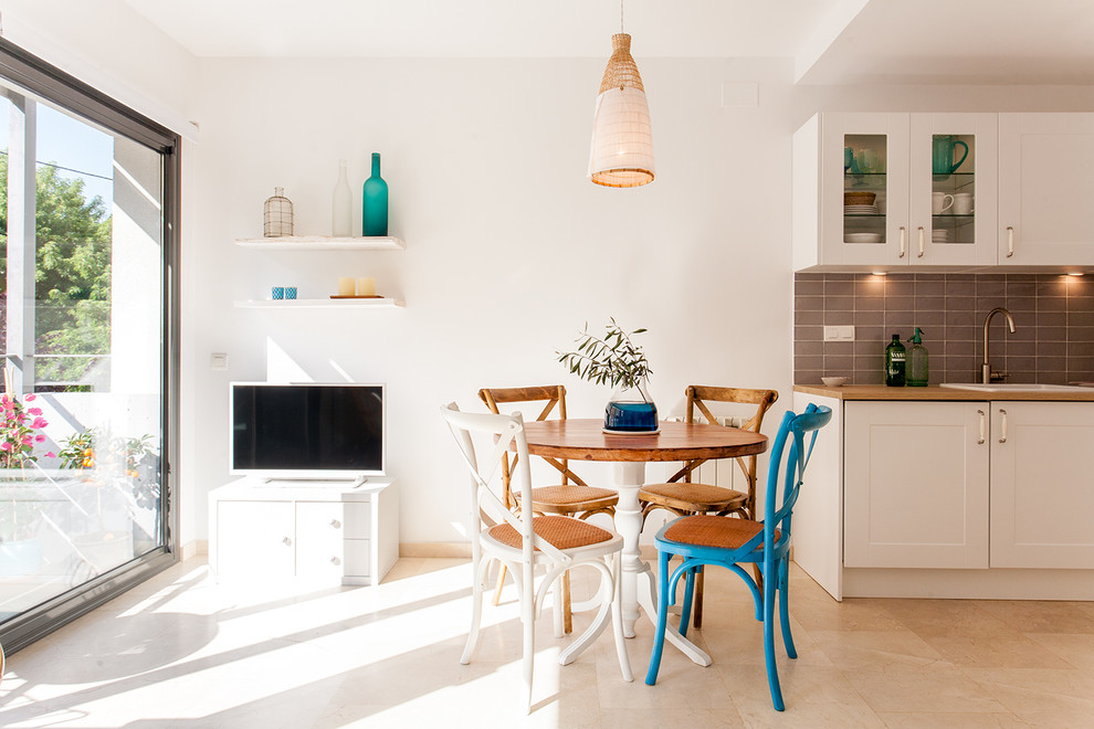 Aménagement d'une petite salle à manger ouverte sur la cuisine méditerranéenne avec un mur blanc, un sol en travertin et un sol beige.