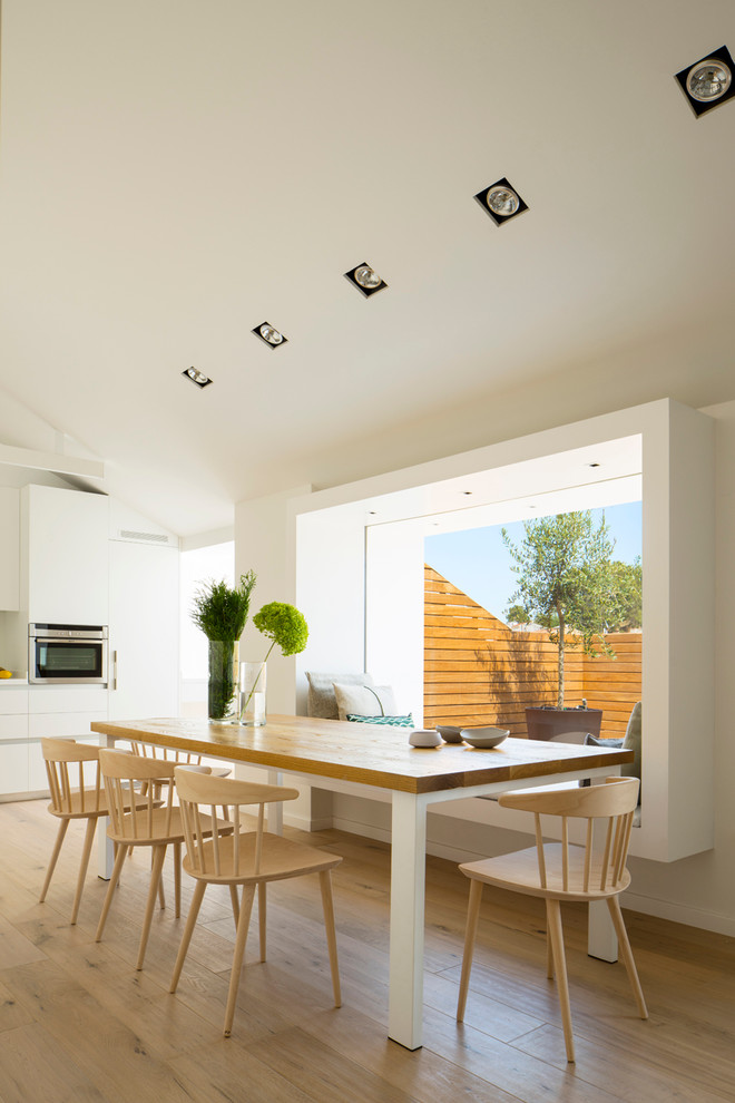 Ejemplo de comedor de cocina contemporáneo de tamaño medio sin chimenea con paredes blancas y suelo de madera clara