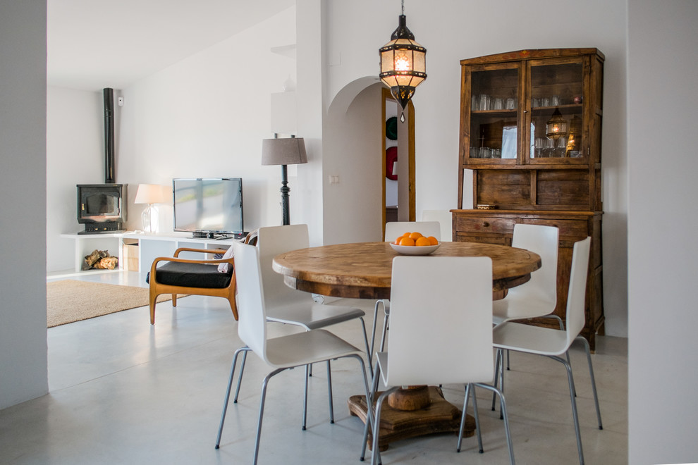 Idée de décoration pour une salle à manger méditerranéenne fermée et de taille moyenne avec un mur blanc et sol en béton ciré.