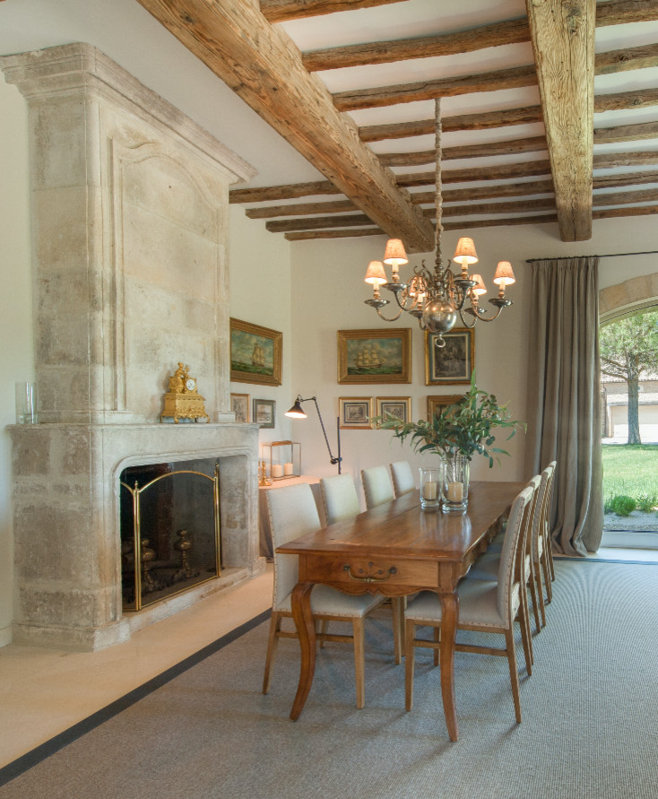 Idée de décoration pour une salle à manger tradition avec une cheminée standard, un manteau de cheminée en pierre et un sol blanc.