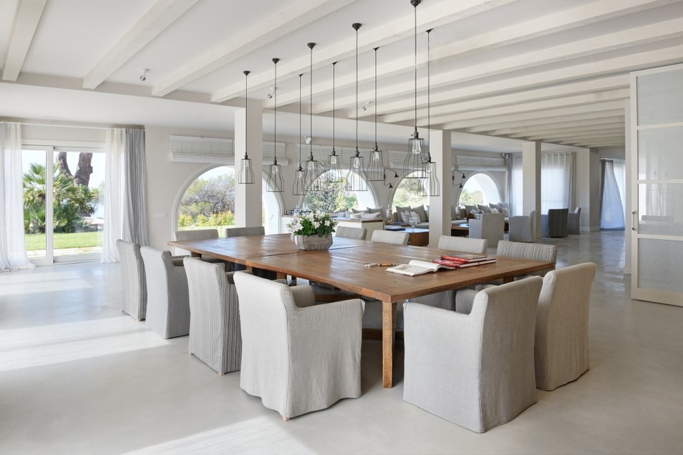 На фото: огромная гостиная-столовая в средиземноморском стиле с белыми стенами без камина с