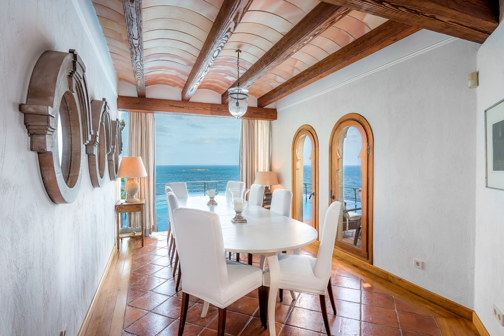 Photo of a medium sized coastal enclosed dining room in Palma de Mallorca with white walls, no fireplace, terracotta flooring and feature lighting.