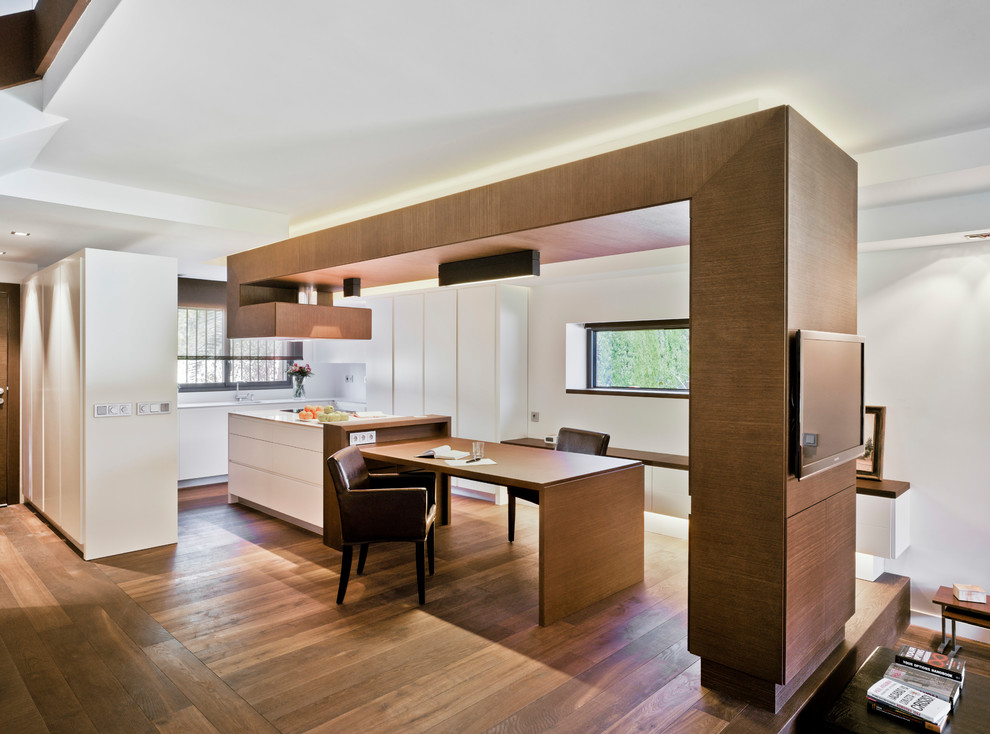 На фото: большая гостиная-столовая в современном стиле с коричневым полом, белыми стенами и темным паркетным полом с