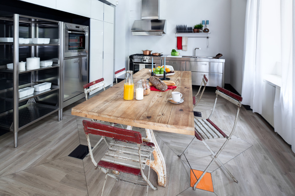 Ejemplo de comedor de cocina industrial de tamaño medio sin chimenea con paredes blancas y suelo de madera en tonos medios