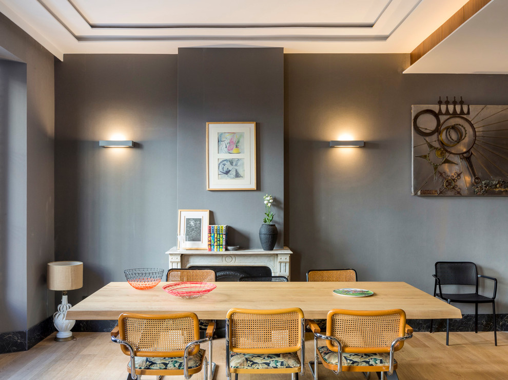 Esempio di una sala da pranzo aperta verso il soggiorno contemporanea con pareti grigie, parquet chiaro, camino classico e pavimento beige