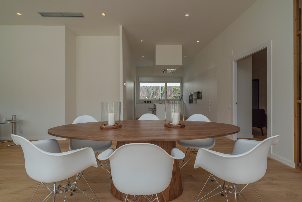Foto di una sala da pranzo aperta verso il soggiorno minimal di medie dimensioni con pareti bianche, pavimento in legno massello medio, camino ad angolo e pavimento marrone