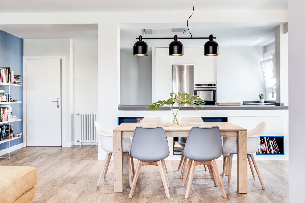 Diseño de comedor escandinavo abierto con paredes blancas, suelo de madera en tonos medios y suelo beige