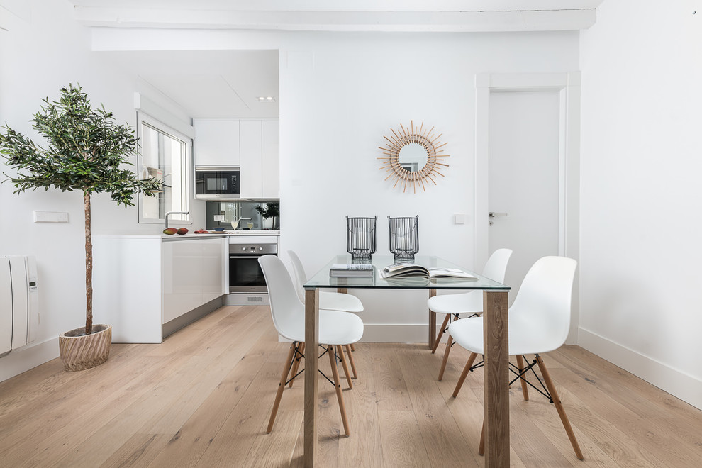 Small scandinavian open plan dining room in Madrid with white walls, light hardwood flooring and beige floors.