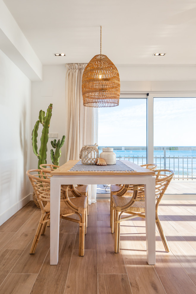 Exemple d'une salle à manger ouverte sur le salon bord de mer de taille moyenne avec un mur blanc et un sol beige.
