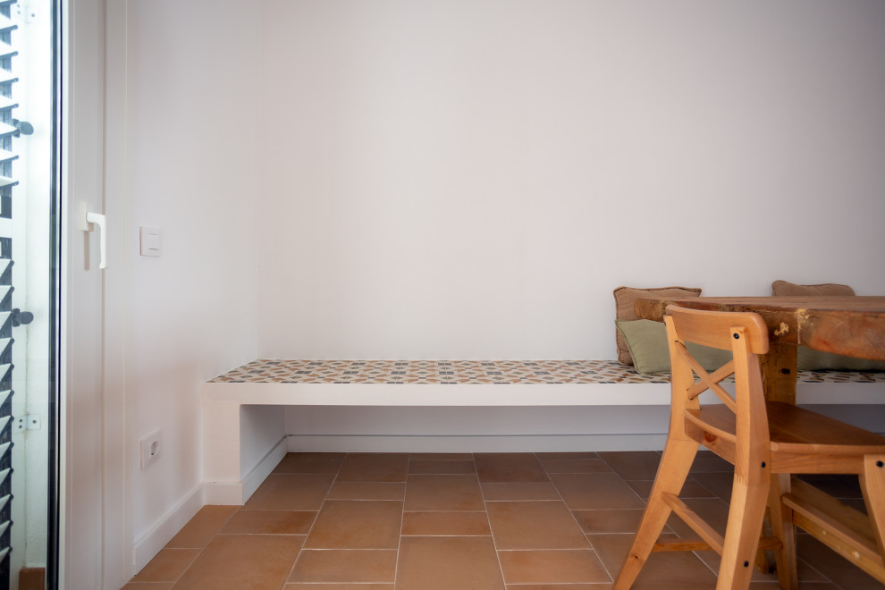 Ejemplo de comedor mediterráneo de tamaño medio abierto con paredes blancas, suelo de baldosas de terracota, chimenea lineal, marco de chimenea de ladrillo y suelo marrón