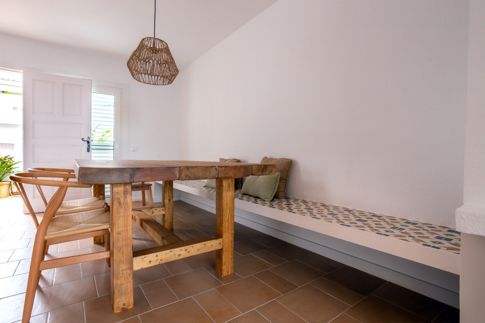Idées déco pour une salle à manger ouverte sur le salon méditerranéenne de taille moyenne avec un mur blanc, tomettes au sol, une cheminée ribbon, un manteau de cheminée en brique et un sol marron.