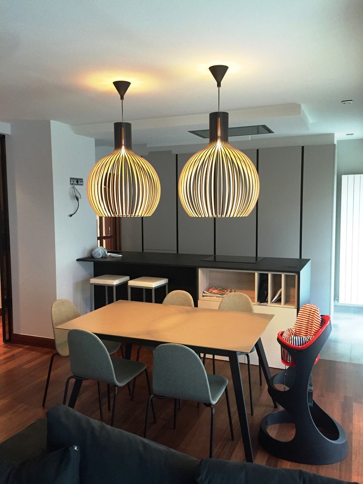Idée de décoration pour une salle à manger ouverte sur le salon minimaliste de taille moyenne avec un mur gris et un sol en bois brun.