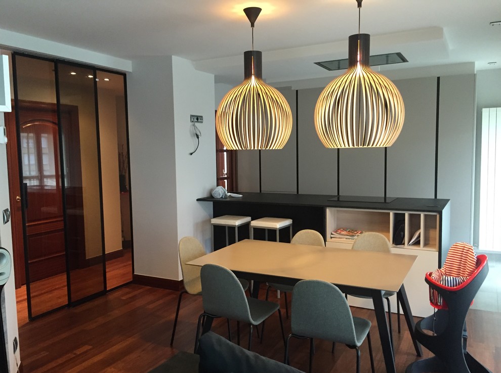 Cette image montre une salle à manger ouverte sur le salon minimaliste de taille moyenne avec un mur gris et un sol en bois brun.