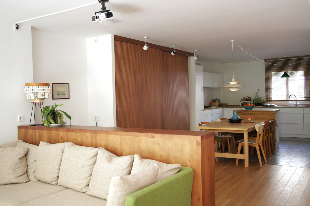 Immagine di una grande sala da pranzo aperta verso la cucina scandinava con pareti bianche e pavimento in legno massello medio