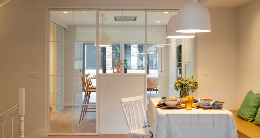 Cette photo montre une salle à manger tendance de taille moyenne avec une banquette d'angle, un mur beige, sol en stratifié, aucune cheminée, un sol beige et du papier peint.