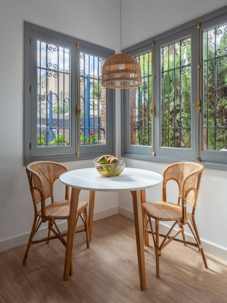 Immagine di una sala da pranzo aperta verso la cucina mediterranea di medie dimensioni con pavimento beige, pareti bianche e parquet chiaro