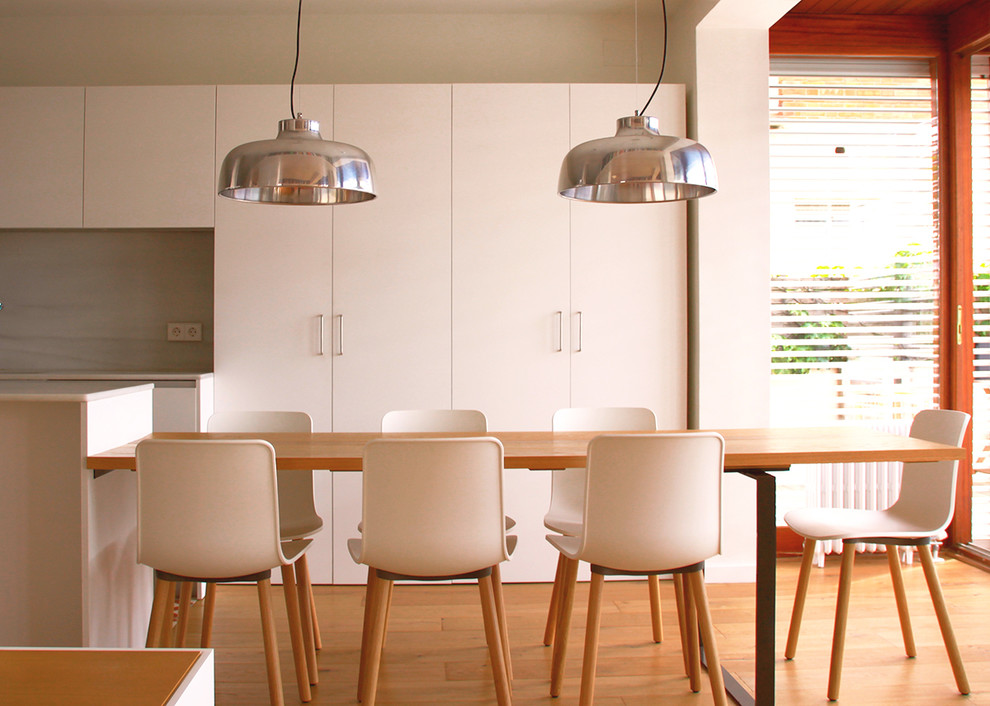 This is an example of a scandinavian dining room in Barcelona with white walls and light hardwood flooring.