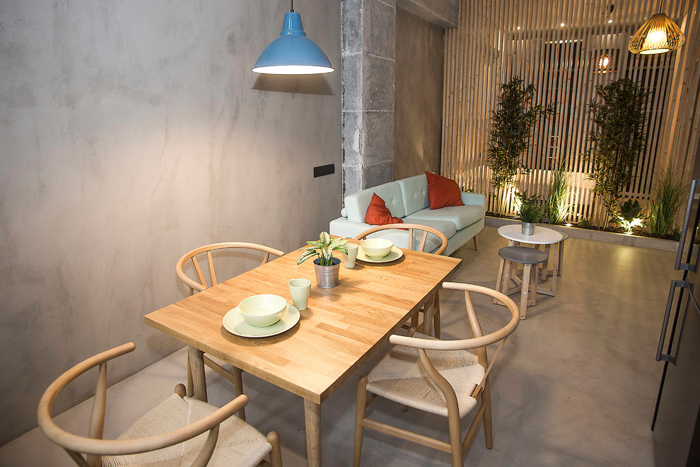 Immagine di una sala da pranzo aperta verso la cucina industriale di medie dimensioni con pareti grigie, pavimento grigio e pavimento in cemento