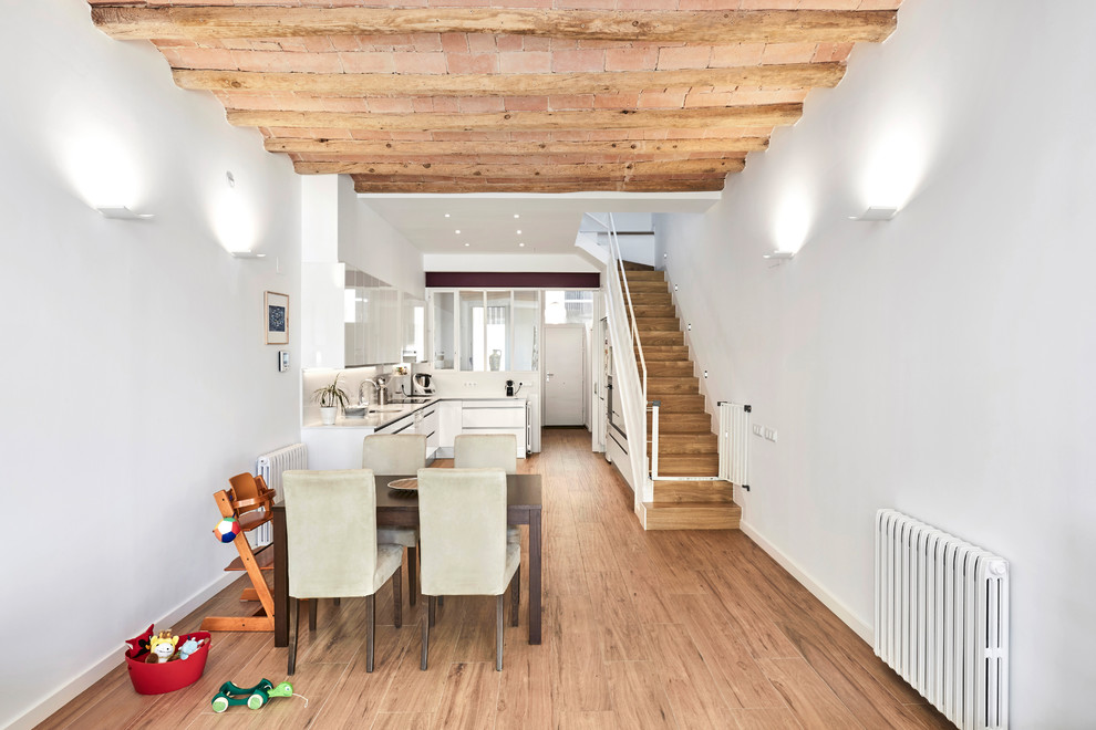 Große Mediterrane Wohnküche ohne Kamin mit weißer Wandfarbe, braunem Holzboden und braunem Boden in Sonstige