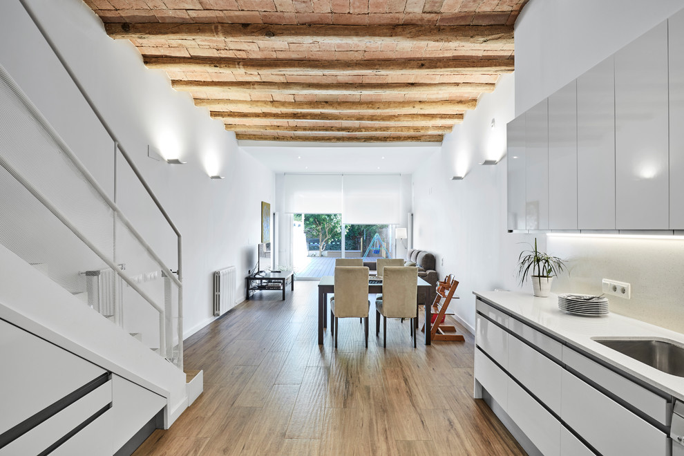 Große Mediterrane Wohnküche ohne Kamin mit weißer Wandfarbe, braunem Holzboden und braunem Boden in Sonstige