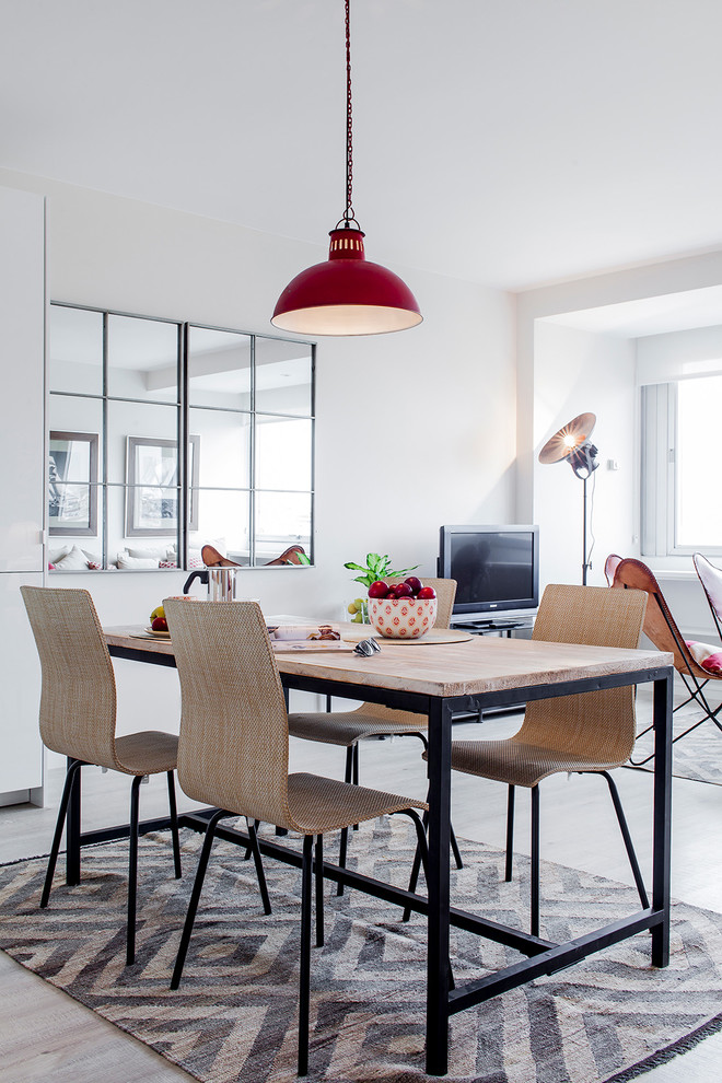 This is an example of a medium sized scandi open plan dining room in Madrid with white walls, light hardwood flooring, no fireplace and feature lighting.