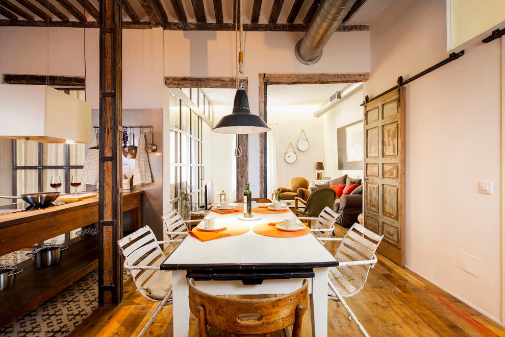 Foto di una grande sala da pranzo aperta verso la cucina boho chic con pareti bianche, pavimento in legno massello medio e nessun camino