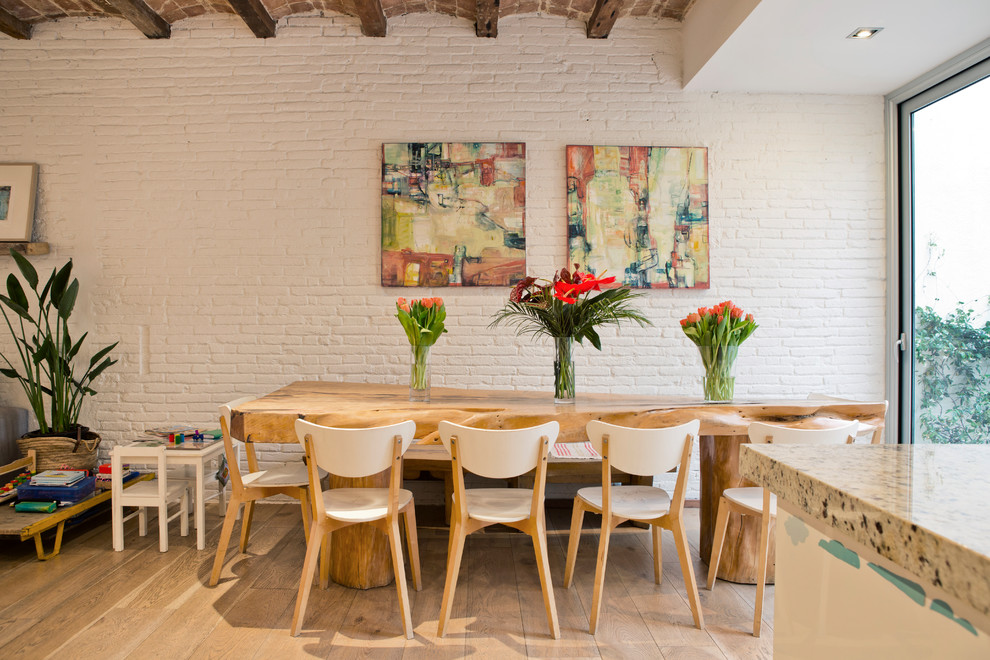 Réalisation d'une salle à manger ouverte sur la cuisine design avec un mur blanc, un sol en bois brun et un sol marron.