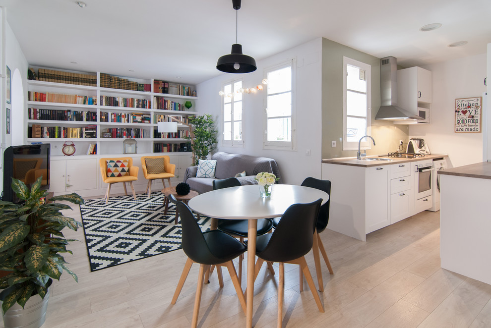 This is an example of a medium sized scandi open plan dining room in Madrid with white walls, light hardwood flooring, no fireplace and beige floors.