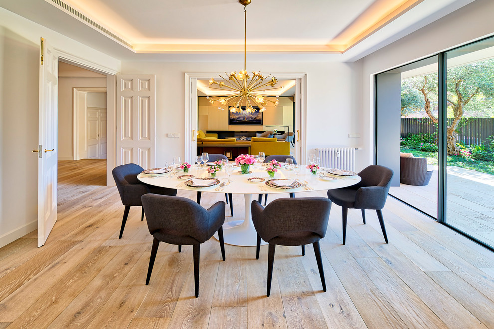 Immagine di una sala da pranzo design chiusa con pareti bianche, parquet chiaro e pavimento beige