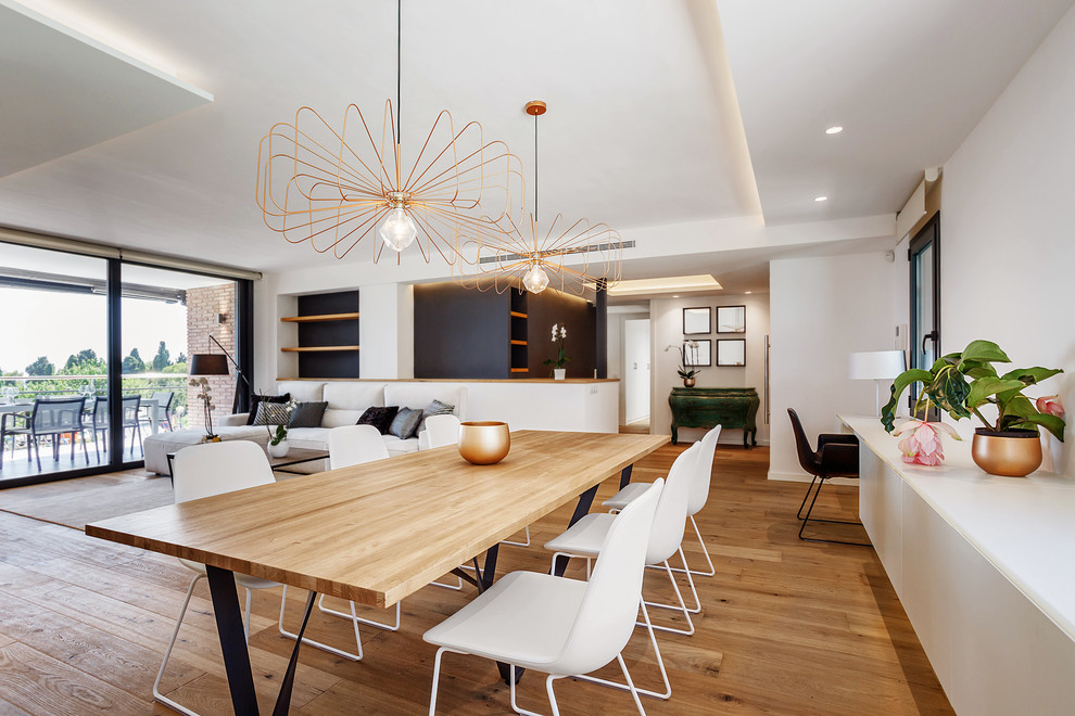 Immagine di una sala da pranzo aperta verso il soggiorno minimal con pareti bianche, pavimento in legno massello medio e pavimento marrone