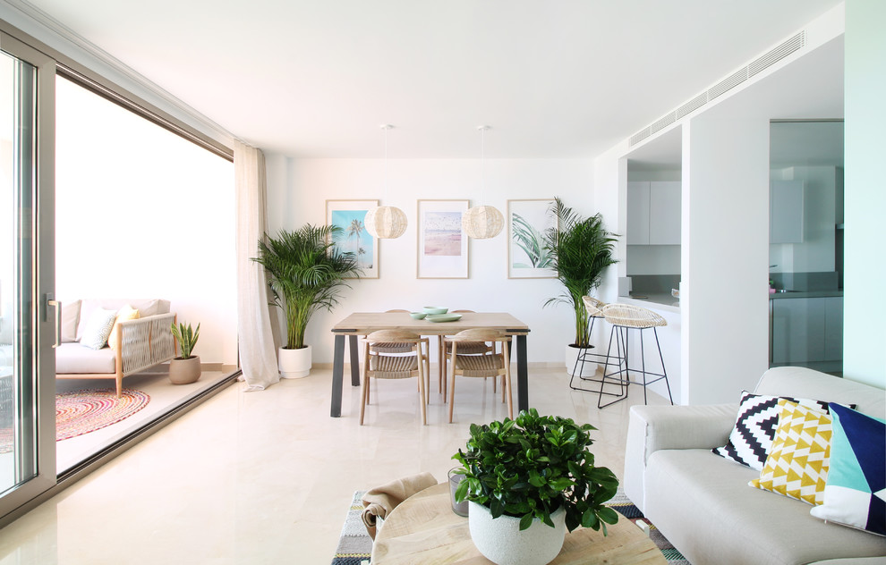 Immagine di una sala da pranzo aperta verso il soggiorno stile marino con pareti bianche, nessun camino e pavimento beige
