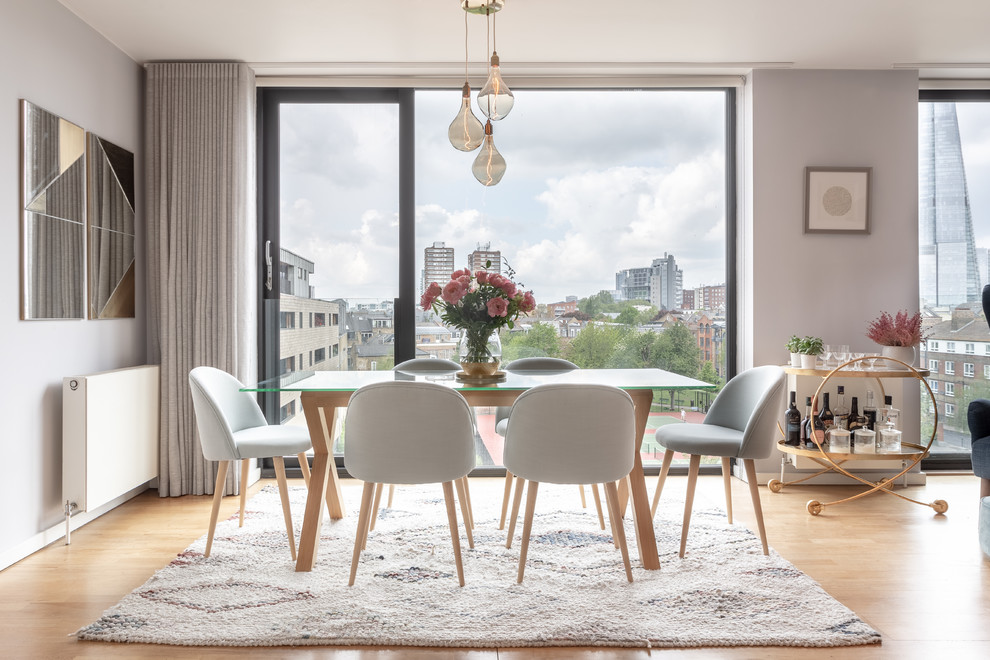 This is an example of a contemporary dining room in London with grey walls, light hardwood flooring and beige floors.